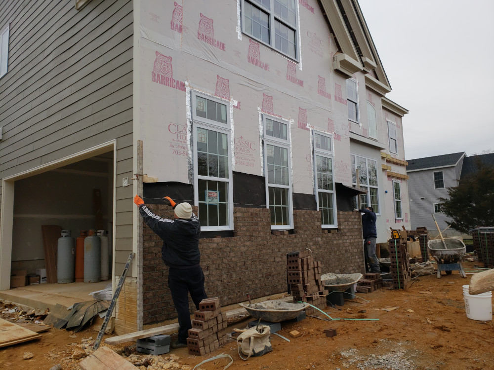 Construction workers laying brick siding
